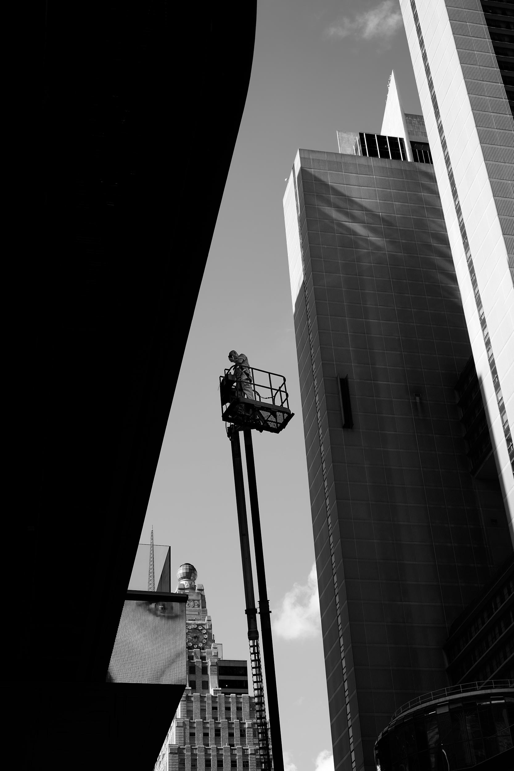 New York City - A worker stands on a lift between tall buildings in Times Square